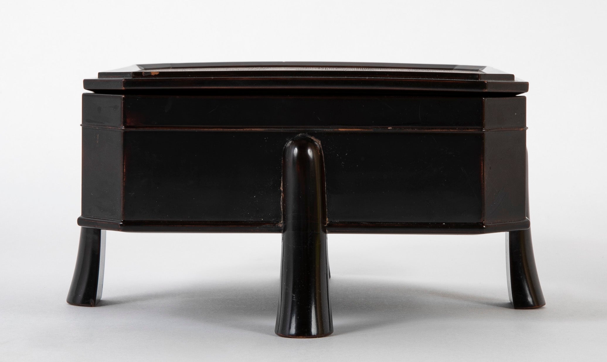 A Japanese Black Lacquer Faceted Covered Box on Four Splayed Feet
