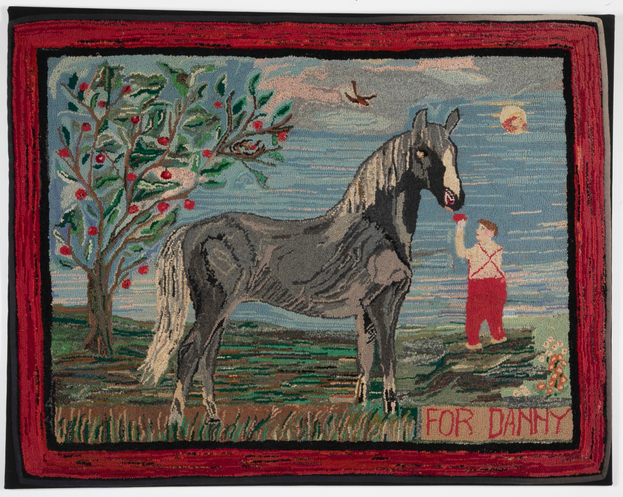 An Exceptional American Hooked Rug Depicting a Boy Feeding an Apple to a Horse