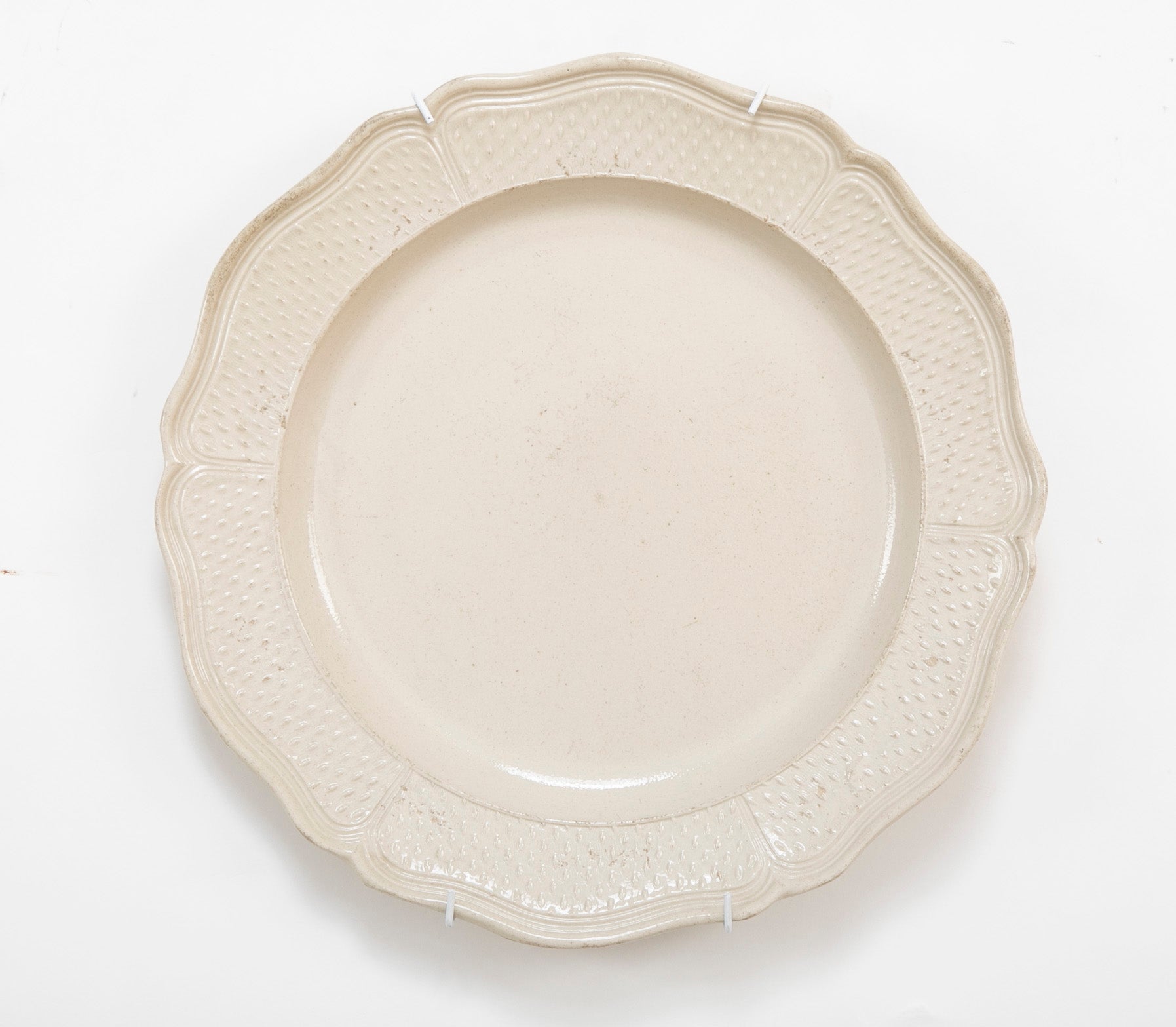 A Salt Glazed Stoneware Charger with Serpentine Border and Dimpled Margin